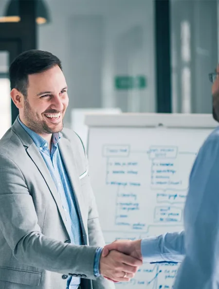 Kanak Capital Markets owner shaking hands during a business meeting with strategy plans in the background.
