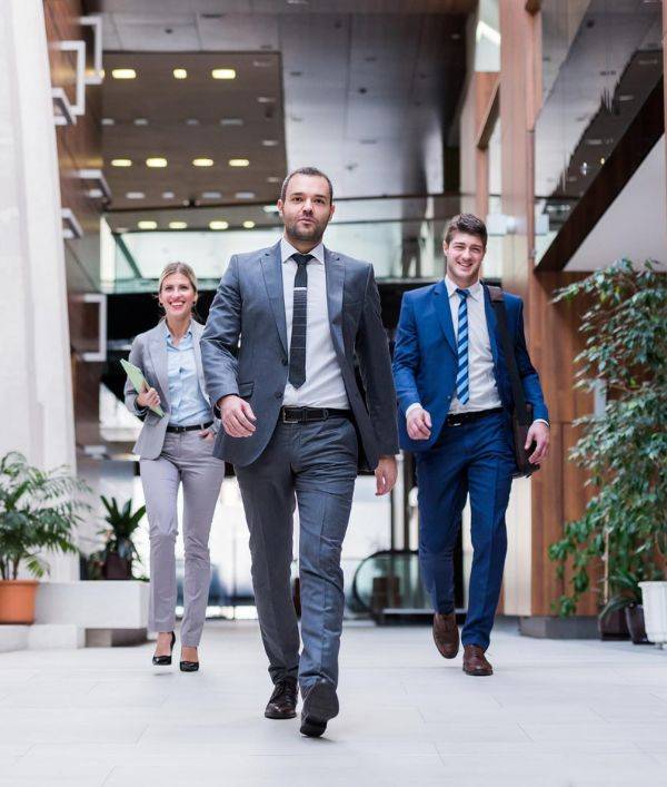 Professional team at Kanak Capital Markets and trading firm walking confidently in a modern office.